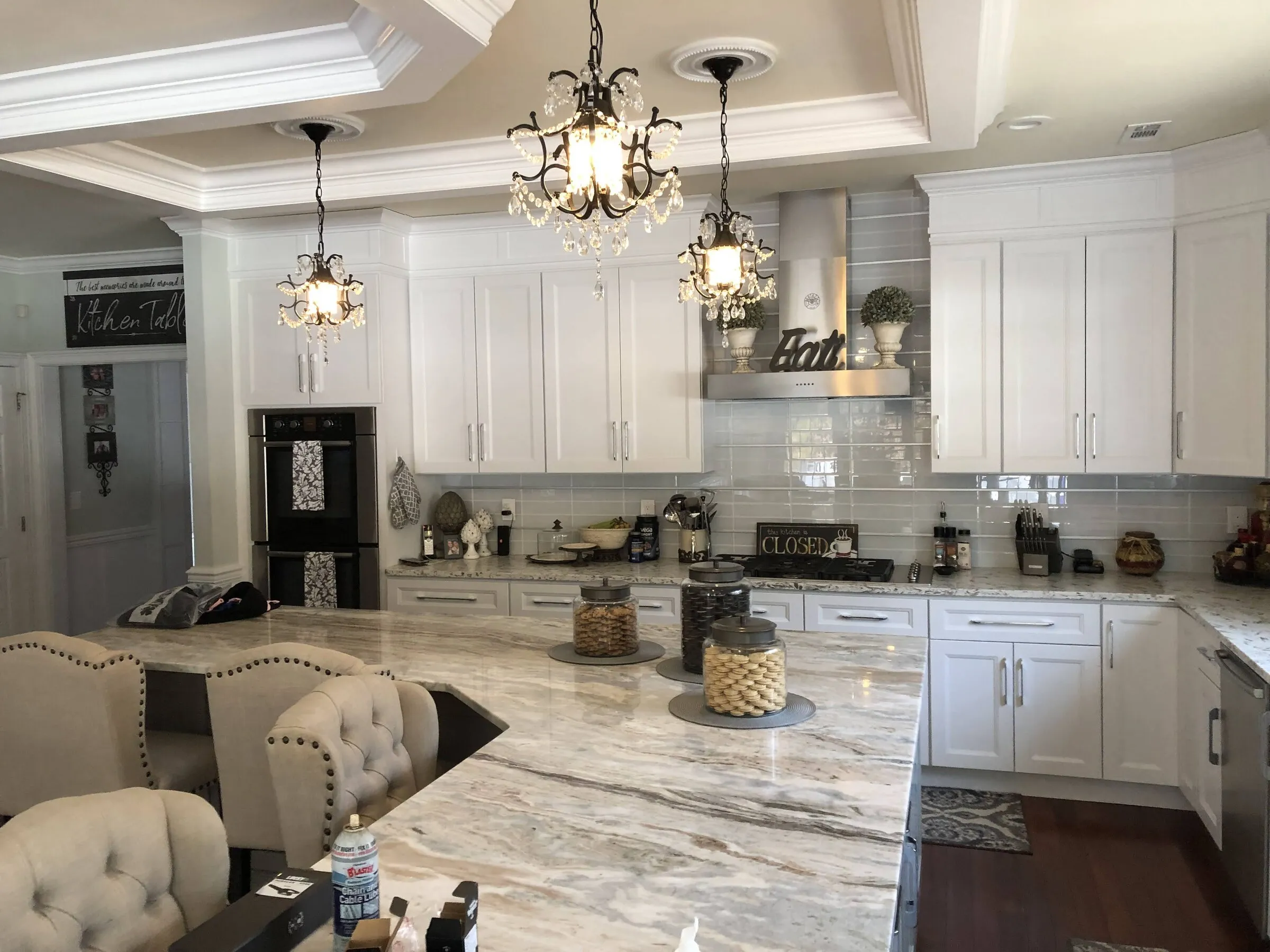 Pendant chandeliers and recessed lighting installed by DTM Electric in a renovated white kitchen
