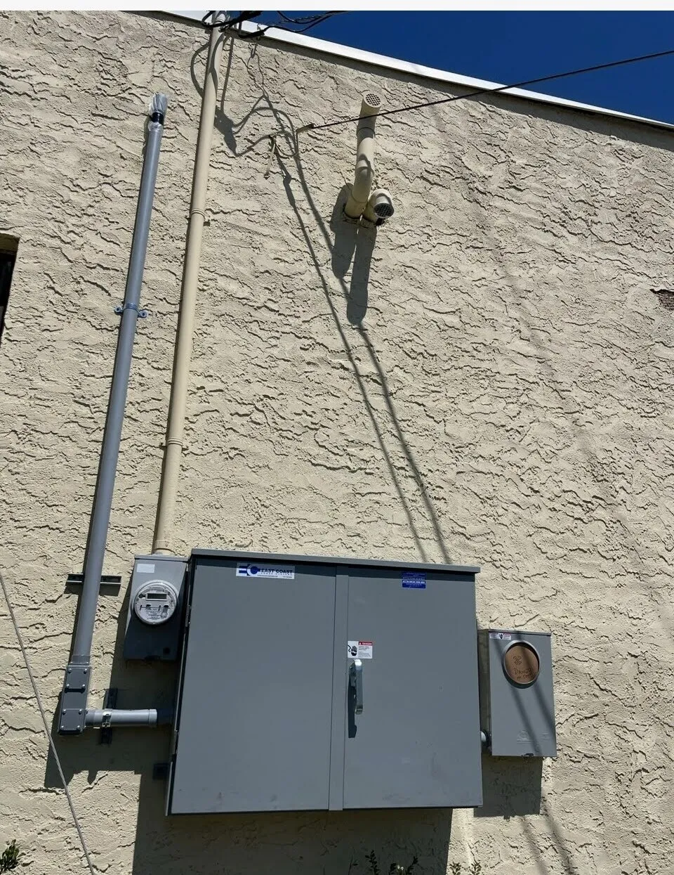 Exterior electric meter and service mast on a stucco home